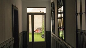 A hallway with a door leading to a small outdoor area with a lawn and a chair.