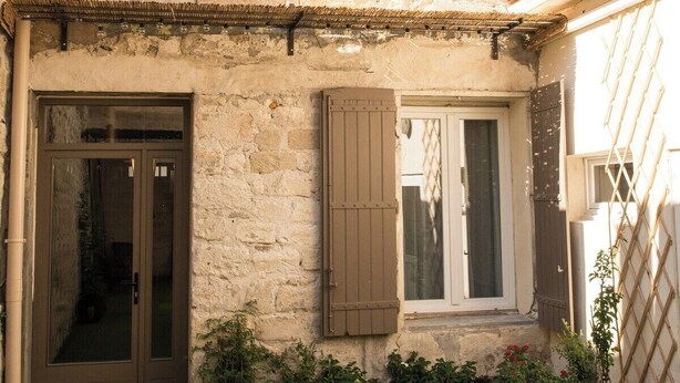 A stone building with a front door, two windows with shutters, and a small balcony. - Suite #4 - a unique 30m2 loft overlooking the inner courtyard (Aigues-Mortes)