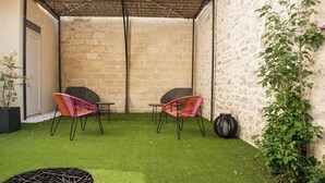 A patio area with artificial grass, two wicker chairs, a table, and a potted plant. - Suite #4 - a unique 30m2 loft overlooking the inner courtyard (Aigues-Mortes)