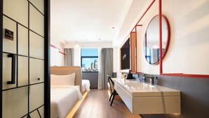A modern hotel room with a bed, a desk, a mirror, and a view of the city. - XIAMEN ZHONGSHAN ROAD  QULISTAR HOTEL (Xiamen)