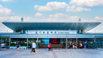 A modern building with a large glass entrance and a sign reading "Xiamen Ferry".