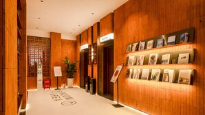 A hotel lobby with wooden paneling, a reception desk, and a wall with informational posters. - XIAMEN ZHONGSHAN ROAD  QULISTAR HOTEL (Xiamen)