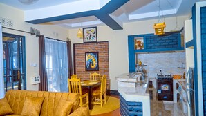Ein modernes Wohnzimmer mit Sofa, Esstisch und Stühlen. Es gibt eine Küchenzeile mit Herd und Spüle.