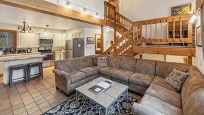 A spacious living area with a large sectional sofa, a coffee table, and a staircase leading to an upper level. - 4 BR Home near Lake: 6 min to Okemo Mtn. (Ludlow)
