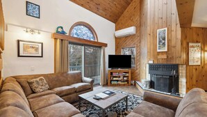 A cozy living room with a fireplace, a television, and a bookshelf. - 4 BR Home near Lake: 6 min to Okemo Mtn. (Ludlow)