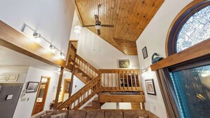 A spacious interior with a wooden staircase, a large window with a view, and a ceiling fan. - 4 BR Home near Lake: 6 min to Okemo Mtn. (Ludlow)