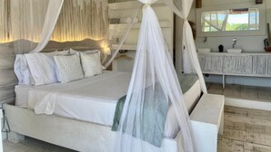 A modern bedroom with a large bed, white bedding, and a canopy. - Hotel Casa Kai (Dibulla)
