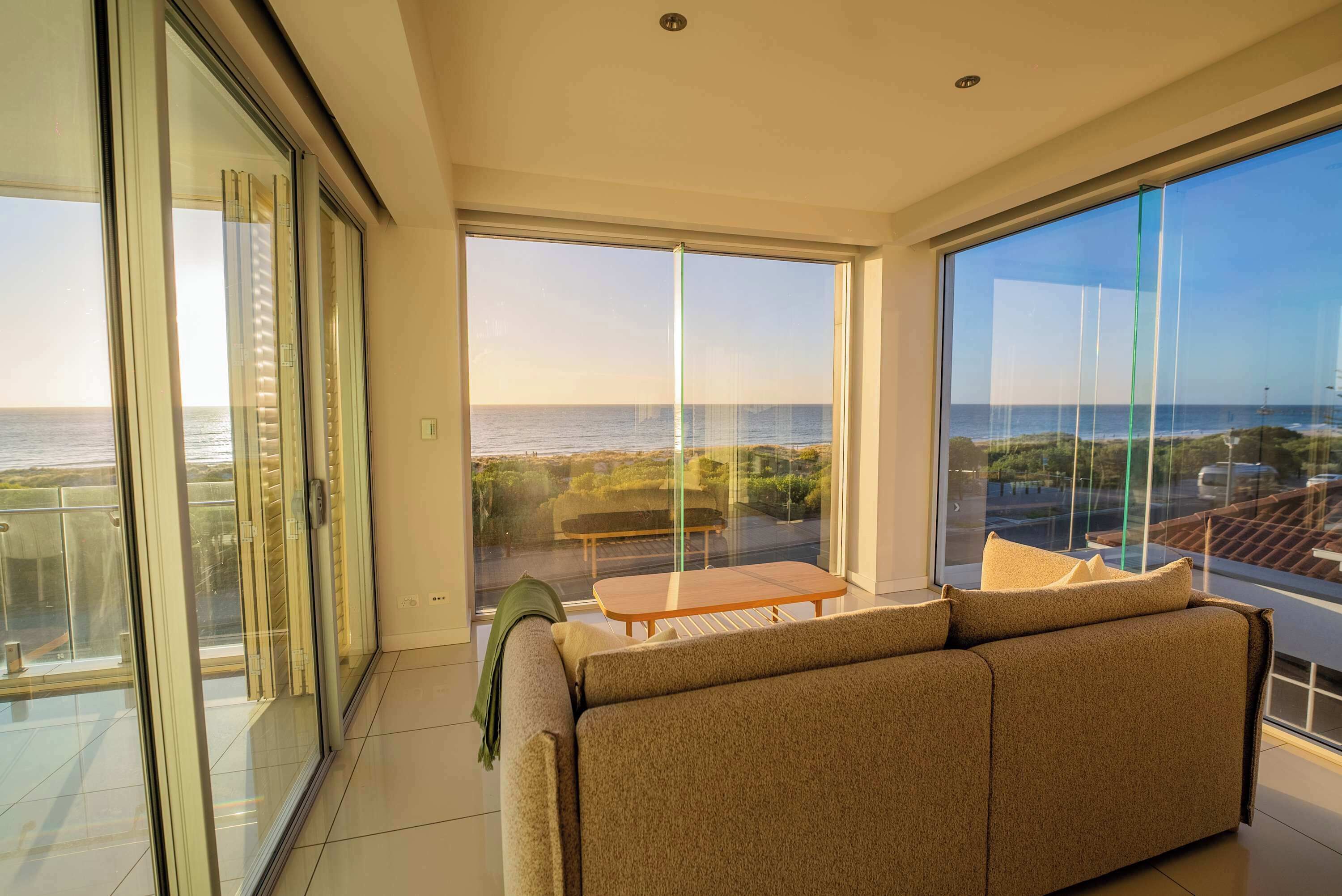 Een moderne woonkamer met een grote schuifpui die uitkomt op een balkon met uitzicht op de oceaan.