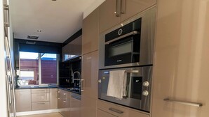 Een moderne keuken met roestvrijstalen apparatuur, waaronder een Bosch oven en een inbouwmagnetron.