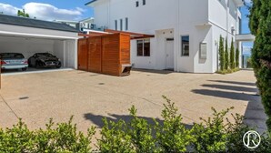 Een modern huis met twee verdiepingen, een garage, een houten schutting en een keurig onderhouden gazon.