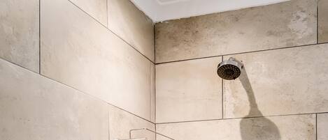 A shower area with beige tiles and a handheld showerhead.
