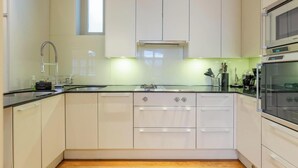 Una cucina moderna con un piano di lavoro nero, elettrodomestici in acciaio inossidabile e mobili bianchi.