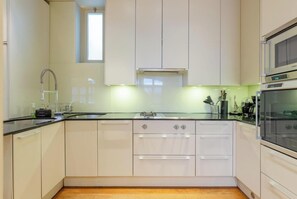 Eine moderne Küche mit schwarzer Arbeitsplatte, Edelstahlgeräten und weißen Schränken.