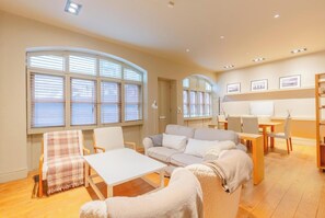 A cozy living room with a sofa, chairs, a table, and a fireplace.