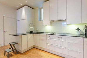 Een moderne keuken met witte kasten, een zwart aanrecht, een roestvrijstalen spoelbak en een ingebouwde oven.