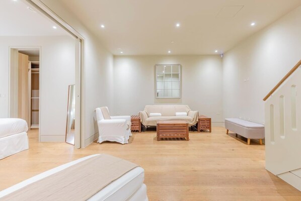 A spacious room with a bed, two chairs, a sofa, a small table, and a window.