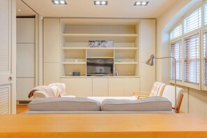 A room with a sofa, a desk, and built-in shelves with books and a TV. - Sublime 4BD House behind V&A, South Kensington (Greater London)