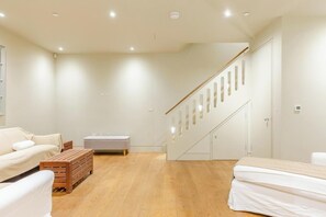 A modern interior with a wooden floor, a staircase, and a white sofa.