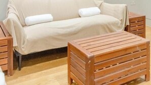 Una stanza con un divano, un tavolino in legno, uno specchio grande e una scala.