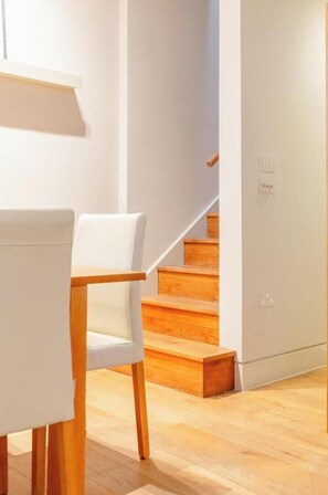 Ein modernes Interieur mit einer Treppe, einem weißen Stuhl und Holzboden.