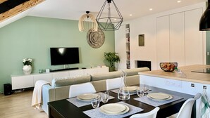 Un soggiorno moderno con zona pranzo, televisione a schermo piatto e libreria.