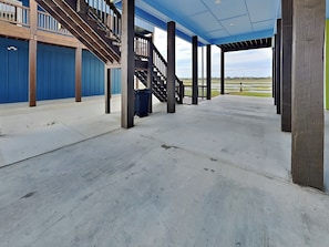 A covered outdoor area with a concrete floor, wooden columns, and a blue railing.