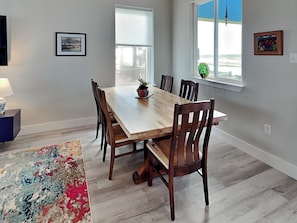 A dining area with a wooden table and chairs, a rug, and artwork on the walls.