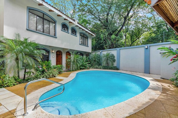 A swimming pool with a curved edge, surrounded by a tiled deck.