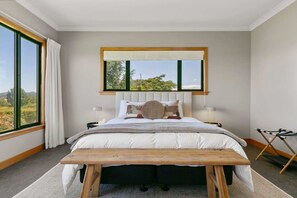 A bedroom with a bed, bedside tables, a window with curtains, and a view of the outdoors. - Watene Lodge - Spacious 5 Star Home with Pool (Taupo)