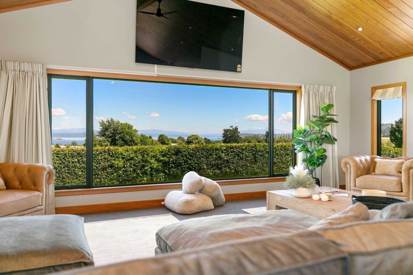 A spacious room with large windows offering a view of a landscaped garden and distant mountains.