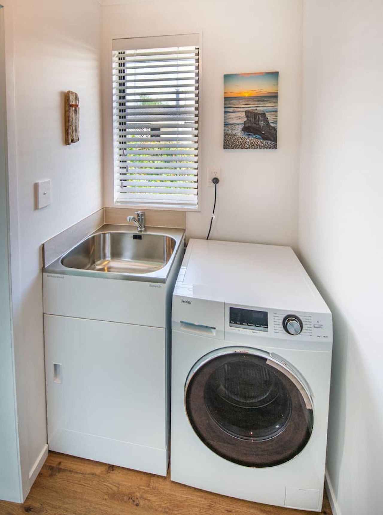 A compact laundry room with a washing machine and a sink.