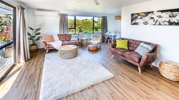 A spacious living room with a large white rug, leather sofas, and a ceiling fan.