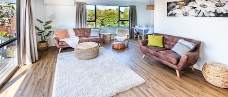 Un salon spacieux avec un grand tapis blanc, des canapés en cuir et un ventilateur de plafond.