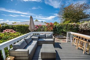 A covered outdoor deck with a wicker sofa, a bench, and a pergola with a canopy. - Taupo Gem: Cozy & Private (Taupo)