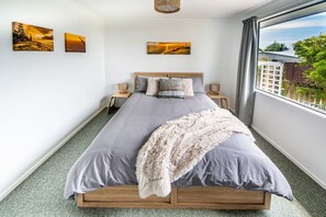 Une chambre à coucher comprenant un lit, deux tables de chevet et trois tableaux accrochés au mur.