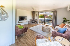 A spacious living room with a fireplace, comfortable seating, a flat-screen TV, and a large sliding glass door leading to an outdoor area.