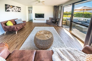 Un salon spacieux doté d’une cheminée, d’un grand téléviseur et d’un balcon aménagé avec du mobilier d’extérieur.
