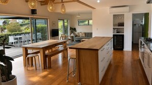 A modern kitchen with wooden countertops, a central island, and a dining area with a large table and chairs.