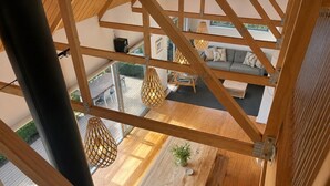 A high-ceilinged room with a wooden table, chairs, and hanging lamps.