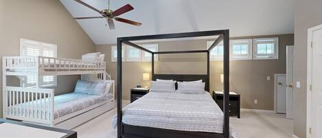 Un dormitorio con cama con dosel, ventilador de techo, literas y un ventanal grande.