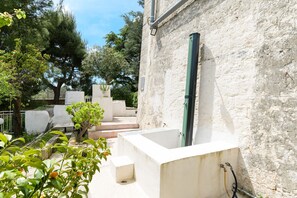 Edifício de pedra com banheira, degraus e vegetação.