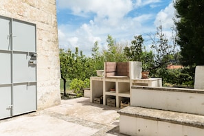 A courtyard with a white wall, a metal door, and a small garden area with potted plants.