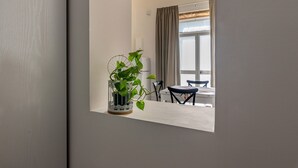 Une pièce comprenant une table à manger, des chaises, une plante en pot et une fenêtre avec des rideaux.