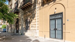 Un bâtiment doté d’une grande entrée en arc de cercle, d’un portail en métal et d’un arbre au premier plan.