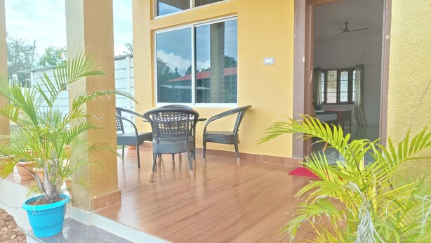 Una habitación con piso de madera, una ventana y una puerta. Hay dos sillas y una mesa.