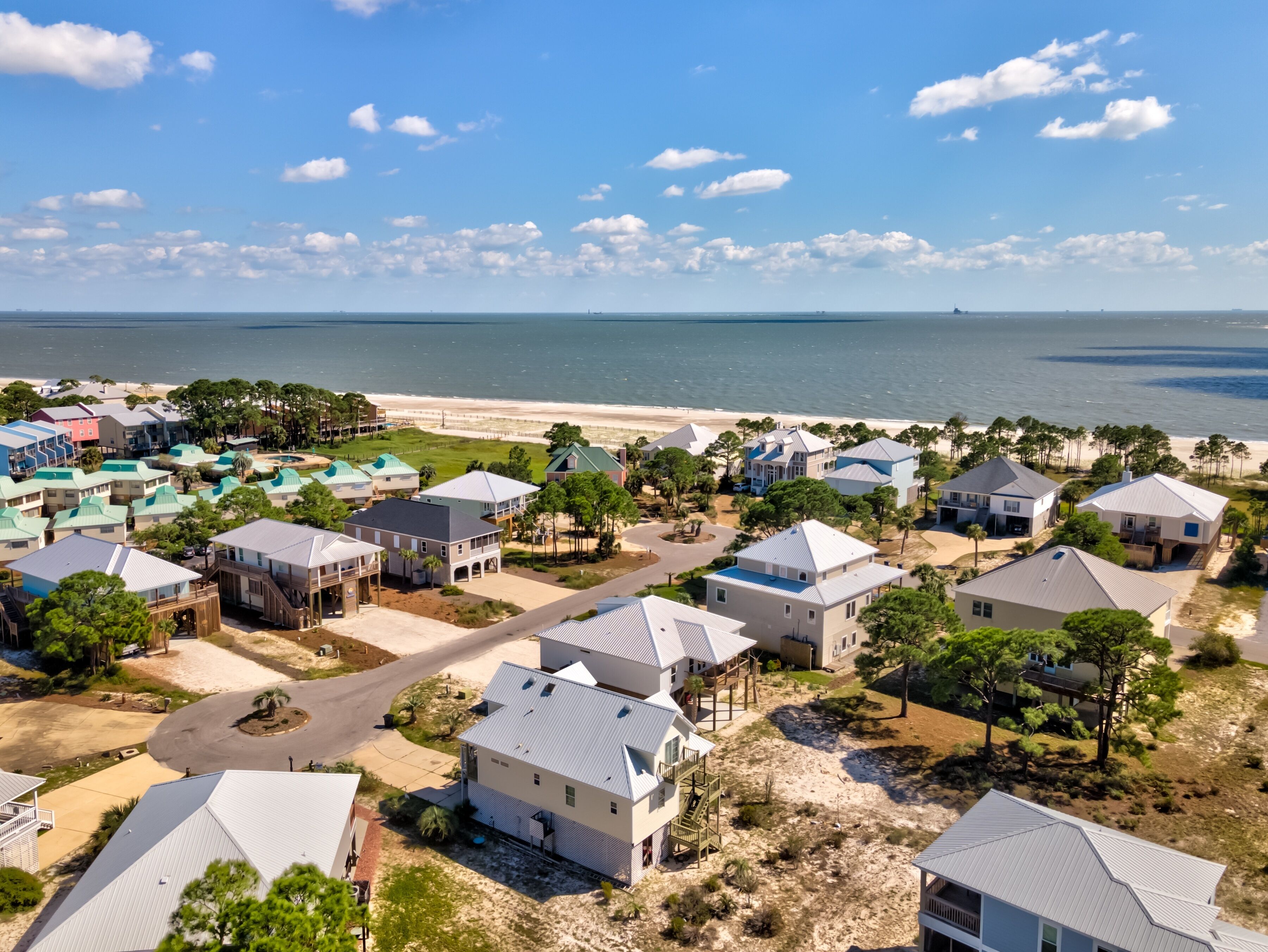 Zona residencial costera con casas, una playa y cielo despejado.
