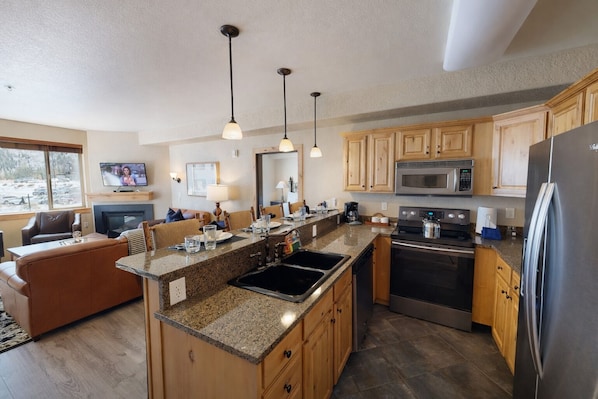 A modern kitchen with granite countertops, wooden cabinets, stainless steel appliances, and pendant lighting. - Silverado Sanctuary 2 Bedroom Condo (Park City)