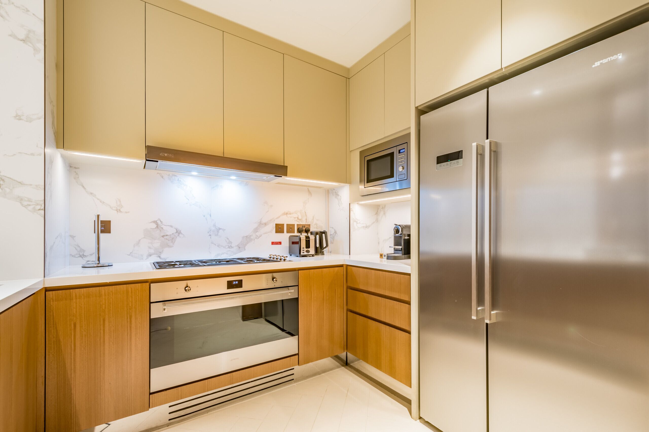 Eine moderne Küche mit Holzausstattung, einem Edelstahl-Kühlschrank, einer Mikrowelle, einem Backofen und einem Gasherd.