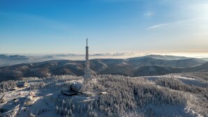 Une station de montagne enneigée, dotée d'un télésiège, de bâtiments et d'une haute tour de communication.