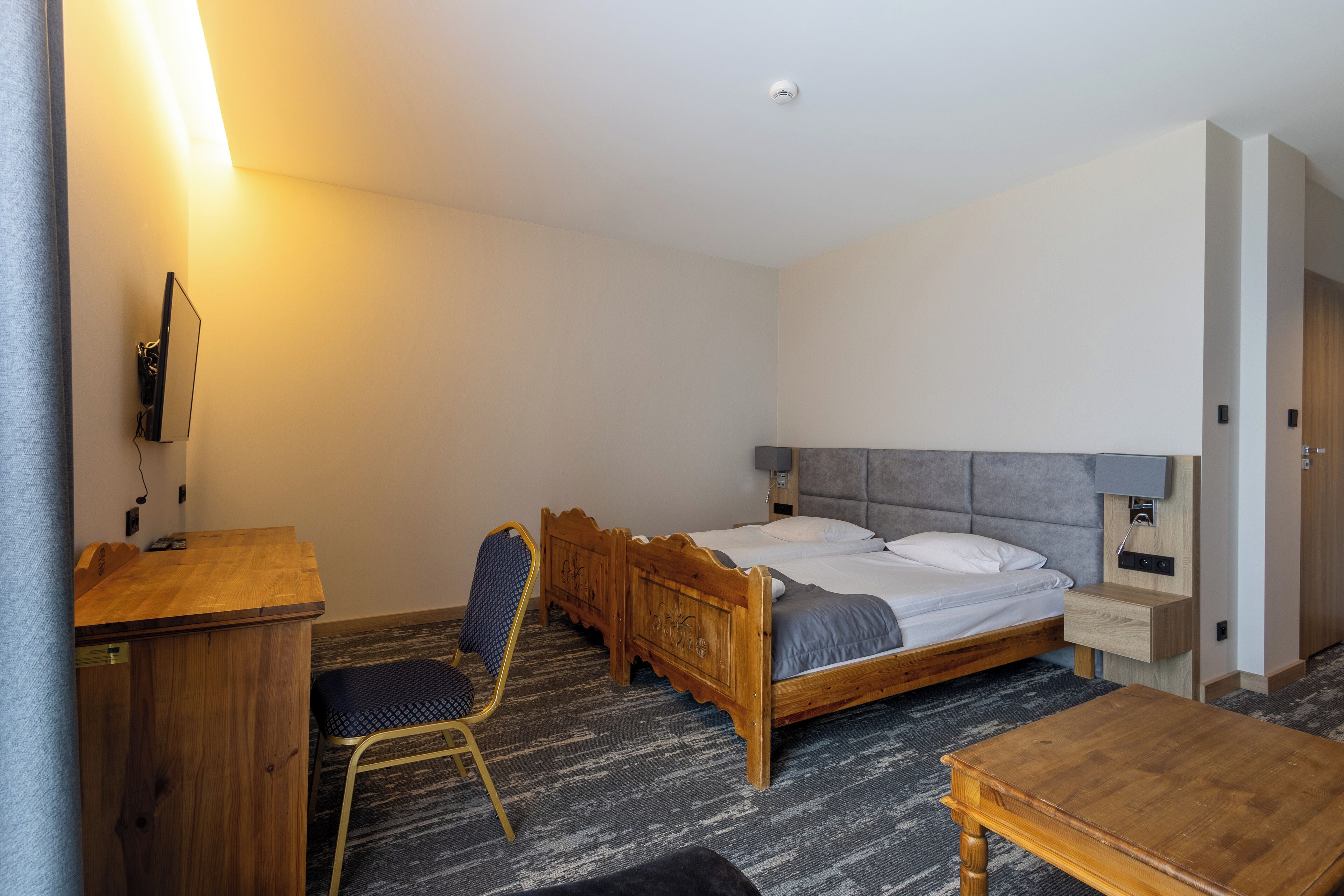 Ein Hotelzimmer mit einem hölzernen Bett, einem Schreibtisch, einem Stuhl und einem kleinen Tisch.